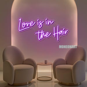 Pu&ograve; includere: Un'insegna al neon viola con la scritta "Love is in the Hair" &egrave; appesa sopra due poltrone beige. Un tavolino rotondo con una tazza &egrave; posizionato tra le sedie. Il muro &egrave; di colore viola chiaro.