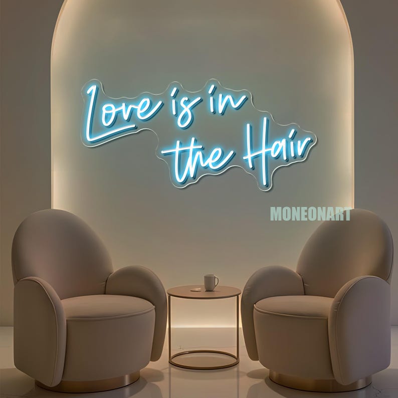 Pu&ograve; includere: Un'insegna al neon blu chiaro con la scritta "Love is in the Hair" su un muro. Due poltrone beige sono disposte una di fronte all'altra, con un tavolino rotondo e una tazza in mezzo. L'insegna &egrave; sopra le sedie.