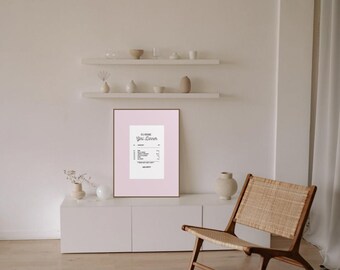 Könnte beinhalten: Ein gerahmter Druck mit rosa Hintergrund, der ein Quittungsdesign mit dem Text "Classic Girl Dinner" zeigt. Der Druck wird auf einem weißen Schrank mit einem Holzstuhl und dekorativen Gegenständen im Hintergrund angezeigt.