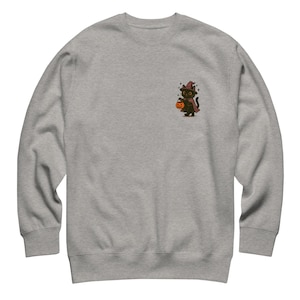 Puede incluir: Una sudadera gris jaspeado con un pequeño gráfico de un gato negro disfrazado de bruja, sosteniendo una linterna de calabaza. El gato lleva un sombrero de bruja y una capa. La sudadera tiene cuello redondo y mangas largas.