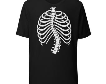 Puede incluir: Camiseta negra con un diseño de caja torácica blanca. El gráfico representa una estructura esquelética detallada del pecho y la columna vertebral. La camiseta es de cuello redondo y parece estar hecha de un material suave.