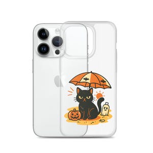May include: Clear phone case with a Halloween design. A black cat sits under an orange umbrella decorated with bats, beside a carved pumpkin and a ghost. The illustration is set on a sandy background with a sun.