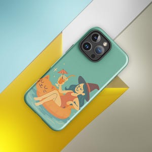 Op de afbeelding: Een turquoise telefoonhoesje met een cartoonillustratie van een heks die ontspant op een katvormige vlotter en een cocktail vasthoudt. De heks draagt een rood badpak en een puntmuts. De hoes heeft een drievoudige cameralens.