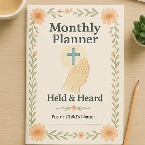 May include: A cream-colored "Monthly Planner" notebook with floral and leaf border. The cover features a cross, praying hands, and the words "Held & Heard". A pencil, a cup of coffee, a keyboard, and a small plant are also visible.