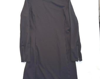 May include: A black long-sleeve dress with a round neckline. The dress features zippers at the cuffs and vertical seams down the front and back. The dress is made of a solid, opaque fabric.
