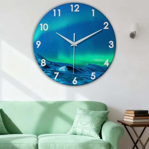 Könnte beinhalten: Runde Wanduhr mit einem Design der blauen und grünen Nordlichter. Das Zifferblatt hat weiße Ziffern und Zeiger. Ein dekoratives Element für ein Wohn- oder Schlafzimmer.