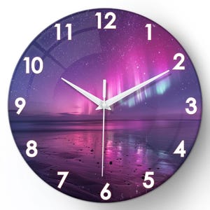 May include: Round wall clock with a purple and pink aurora borealis design. The clock face features white numerals and hands, with a beach scene at the bottom. A decorative piece for any room.