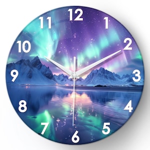 Op de afbeelding: Ronde wandklok met een schilderachtig landschap met een levendige aurora borealis-weergave in tinten van teal, paars en roze. Witte wijzers en cijfers staan tegen de kleurrijke achtergrond. De klok heeft ook besneeuwde bergen en een reflecterend water.