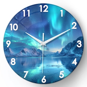Op de afbeelding: Een ronde wandklok met een landschap met een meer en besneeuwde bergen onder een levendig noorderlicht. De klok heeft witte cijfers en wijzers, met een glasachtige afwerking. De klok heeft een diameter van ongeveer 30 cm.
