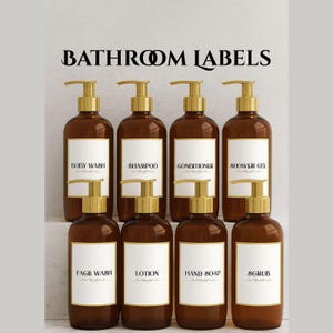 Pode incluir: Um conjunto de frascos de produtos de banho em vidro castanho com dispensadores de bomba dourados. Cada frasco tem um rótulo branco com texto preto indicando o conteúdo, incluindo "SHAMPOO" e "GEL DE DUCHE". As palavras "BATHROOM LABELS" estão no topo.