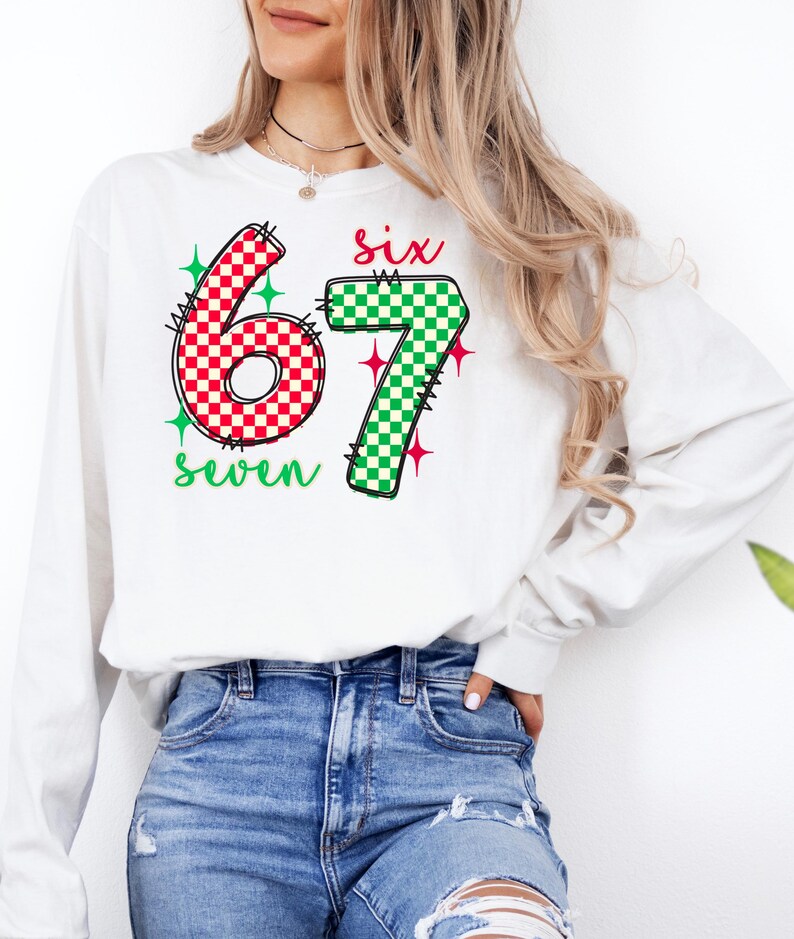 A woman wearing a white long-sleeved shirt with a graphic design featuring the number 67 and the text "Six seven" printed on it.