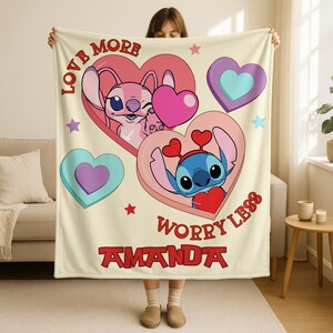 A person holding a blanket with a design featuring two cartoon characters from the Lilo & Stitch movie franchise.