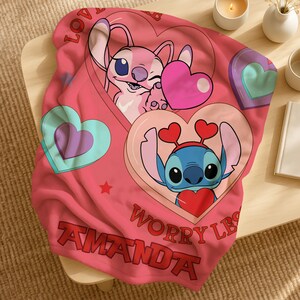 A pink blanket with a cartoon character design, featuring a pink bunny and a blue bunny holding hearts. The blanket also has the text "Worry LBS" and "Amanda" printed on it.