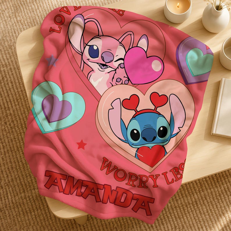 A pink blanket with a cartoon character design, featuring a pink bunny and a blue bunny holding hearts. The blanket also has the text "Worry LBS" and "Amanda" printed on it.