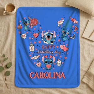 A blue blanket with a Valentine's Day theme, featuring illustrations of characters from the Lilo & Stitch animated series. The blanket has a personalized name, "Carolina", printed on it.