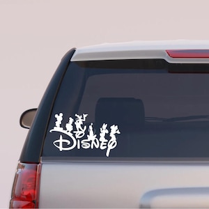 May include: White vinyl decal featuring the Disney logo and silhouettes of Mickey Mouse, Minnie Mouse, Donald Duck, and other characters. The decal is applied to the rear window of a vehicle.