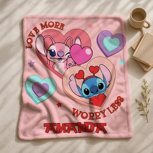 A pink blanket with a cartoon character design, featuring hearts and the text "LOVE MORE WORRY LESS" along with the name "AMANDA".