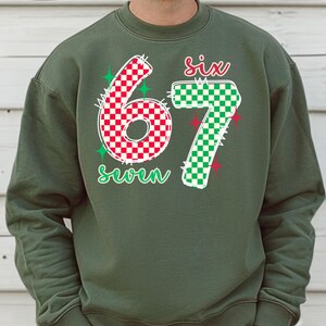 A man wearing a green sweatshirt with the number 67 and the text "six seven" printed on it.
