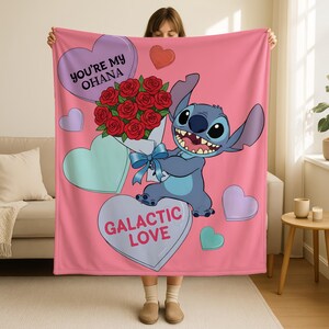 A person is holding up a pink blanket with a cartoon character and a bouquet of red roses. The blanket has a message that says "You're my Ohana" and "Galactic Love".