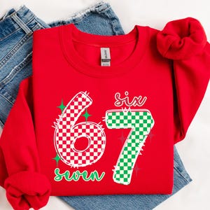 A red sweatshirt with the number "67" printed on it, along with the text "Six seven" in green and white.
