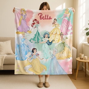 May include: A soft, colorful blanket featuring illustrations of various princesses. The blanket has a pastel background with the name "Bella" in a cursive font. The princesses are depicted in their iconic gowns.