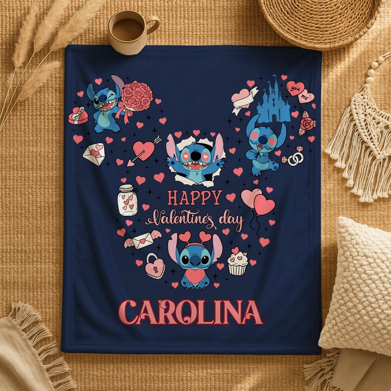 A blue blanket with a Valentine's Day-themed design, featuring characters from the Lilo and Stitch movie franchise, along with various heart-shaped and heart-studded objects. The blanket also has the text "Happy Valentine's day" and "Carolina" printed on it.