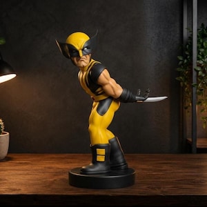 Puede incluir: Una figura coleccionable del personaje Wolverine, representado con un traje amarillo y negro y una máscara con orejas puntiagudas. La figura está en una pose dinámica, inclinada hacia adelante con un brazo extendido, mostrando una garra plateada.