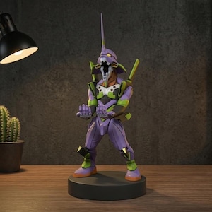 May include: A purple and green humanoid robot figurine standing on a circular black base. The figure features a pointed head, an open mouth, and extended hands. It is colored with purple armor plating, bright green accents, and orange details on the feet.