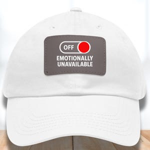 May include: White baseball cap with a gray patch featuring the text "OFF EMOTIONALLY UNAVAILABLE" and a red circle. The cap is made of a soft material and has a curved brim. The patch resembles an on/off switch.