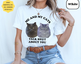 Pode incluir: Camiseta branca com o texto "ME AND MY CATS TALK SH*T ABOUT YOU" e imagens de dois gatos. A camiseta tem gola redonda e mangas curtas. A palavra "White" está em uma caixa preta.