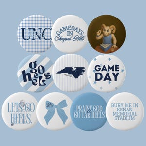 Könnte beinhalten: Eine Sammlung runder Buttons in Blau und Weiß mit verschiedenen Designs und Texten. Die Buttons zeigen Sätze wie "UNC", "Gamedays in Chapel Hill" und "Go Heels". Einige Buttons haben ein Vichy-Muster, Sterne oder eine Schleife.