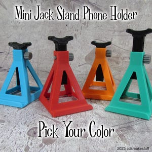 May include: Four mini jack stand phone holders in different colors: blue, red, orange, and green. The stands are made of plastic and have a black metal screw. The text "Pick Your Color" is printed below the stands.
