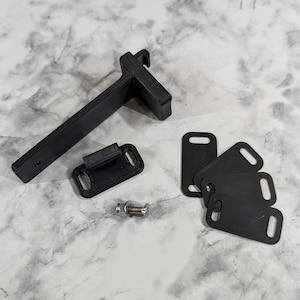 May include: A set of black 3D printed parts for a project. The set includes a bracket, a small rectangular piece with a slot, and four small rectangular pieces with holes. A silver screw is also included.