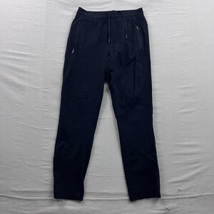 Op de afbeelding: Marineblauwe sportbroek met een tailleband met trekkoord en twee zakken met ritssluiting. De broek heeft een relaxte pasvorm en is gemaakt van lichtgewicht materiaal. Geschikt voor hardlopen, yoga of vrijetijdskleding.