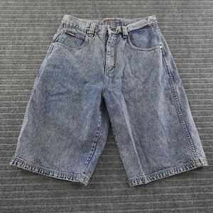 May include: Acid-washed blue denim shorts featuring a high-waisted fit, a button and zipper fly closure, five pockets, and belt loops. The fabric has a distinct mottled light and dark blue texture with visible stitching along the seams.