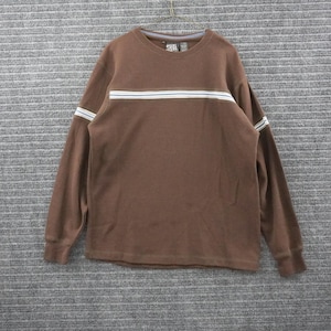 Op de afbeelding: Een bruin shirt met lange mouwen en een ronde hals, gemaakt van een gewafelde stof met textuur. Het shirt heeft een horizontaal streeppatroon over de borst en mouwen in de kleuren lichtblauw, wit en donkerbruin. Een klein merklabel is zichtbaar.