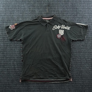 May include: A dark gray short-sleeve polo shirt featuring the white embroidered text Ecko Unltd. on the chest. The shirt includes various circular and shield-shaped patches, a collar with a button placket, and horizontal stripes along the bottom hem.