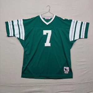Pode incluir: Uma camisola de futebol verde com o número 7 branco na frente. A camisola tem riscas brancas nas mangas e um decote em V. A camisola está pendurada num cabide de metal.
