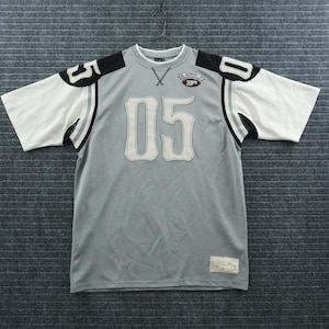 May include: A grey short-sleeve athletic jersey featuring white number 05 appliqués on the chest and shoulders. The shirt has black shoulder panels, white sleeves with black and grey stripes, a crew neckline with a cross-stitch detail, and a small patch.