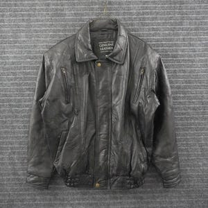 Puede incluir: Una chaqueta de cuero negro con cuello, mangas largas y cierre frontal de cremallera. La chaqueta incluye dos bolsillos verticales con cremallera en el pecho y un botón en el dobladillo inferior. La etiqueta interior dice Italian Design GENUINE LEATHER.
