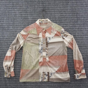 May include: A long-sleeve button-up shirt featuring a geometric pattern in shades of cream, sage green, brown, and muted orange. The shirt has a pointed collar, a partial front button placket with gold-toned buttons, and buttoned cuffs.