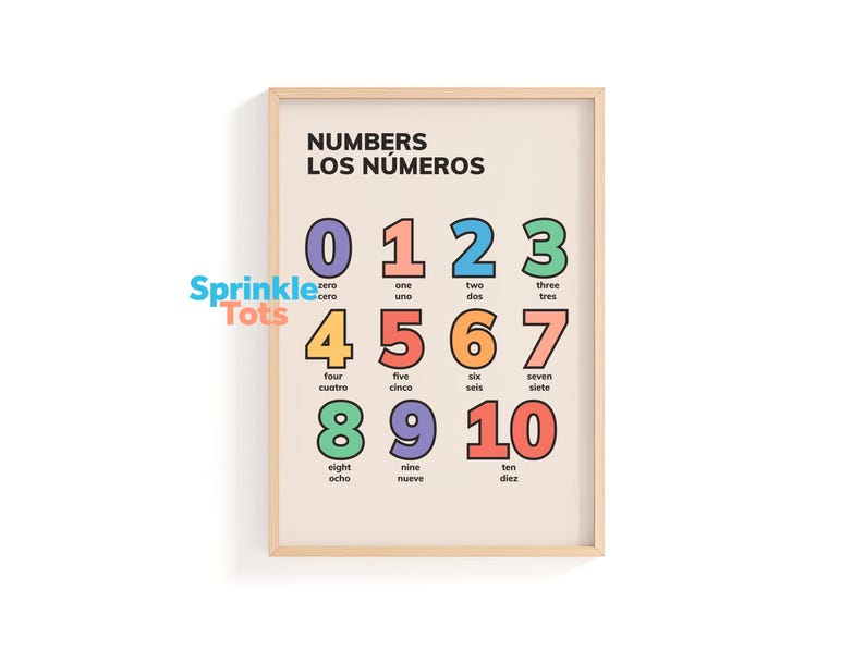 May include: A framed educational print featuring numbers 0-10 in English and Spanish. Each number is displayed in a different color with its corresponding word in both languages. The print has a beige background and a wooden frame.