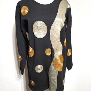 May include: Black long-sleeved sweater with gold and silver sequins in a polka dot and wavy pattern.