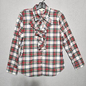 May include: A white, red, green, and blue plaid long-sleeved button-up shirt with a ruffled collar.