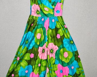 Könnte beinhalten: Ein ärmelloser Jumpsuit mit einem lebendigen Blumenmuster in leuchtendem Grün, Türkis und Pink. Das Kleidungsstück hat einen tiefen V-Ausschnitt, ein eng anliegendes Oberteil und eine weit geschnittene Hose, die ab der Taille ausgestellt ist.