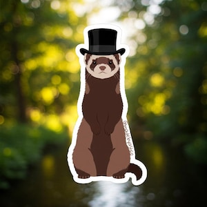 May include: A sticker featuring a cartoon ferret wearing a black top hat. The ferret is depicted in shades of brown and tan, with a white outline. The background is a blurred image of green foliage.