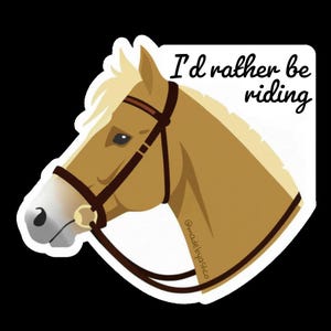 Puede incluir: Una pegatina con la cabeza de un caballo en tonos beige y crema, con una brida marr&oacute;n. El texto "I'd rather be riding" est&aacute; escrito en negro sobre la cabeza del caballo. La pegatina tiene un borde blanco y un fondo negro.