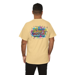May include: A light yellow short-sleeved t-shirt featuring a colourful graphic on the back. The design includes the text "I TOLD CHATGPT ABOUT YOU" in a bold, multi-coloured graffiti style, surrounded by vibrant paint splatters and black line art.