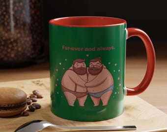 Puede incluir: Taza de cerámica verde con interior y asa rojos. La taza presenta una ilustración de dos figuras de dibujos animados abrazándose en ropa interior, con el texto "Fur-ever and always". Pequeños corazones rosas dispersos.