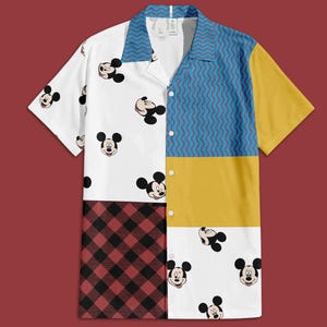 Puede incluir: Una camisa de manga corta con un diseño de patchwork. La camisa presenta un panel blanco con caras de Mickey Mouse, un panel azul y amarillo y un panel a cuadros rojo y negro. El cuello es azul con un patrón de ondas.
